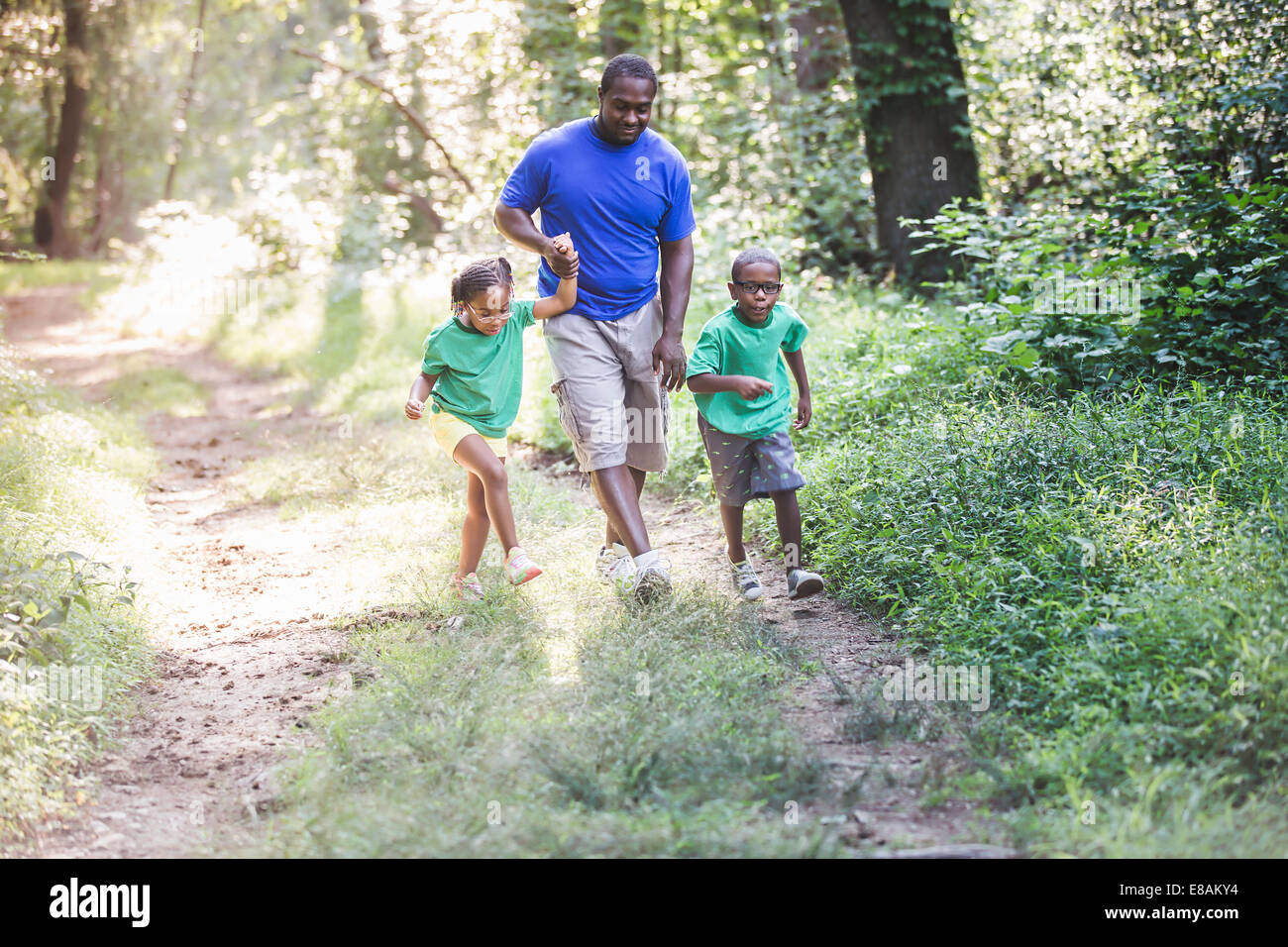 Padre camminare attraverso la foresta con la figlia e il figlio a eco camp Foto Stock