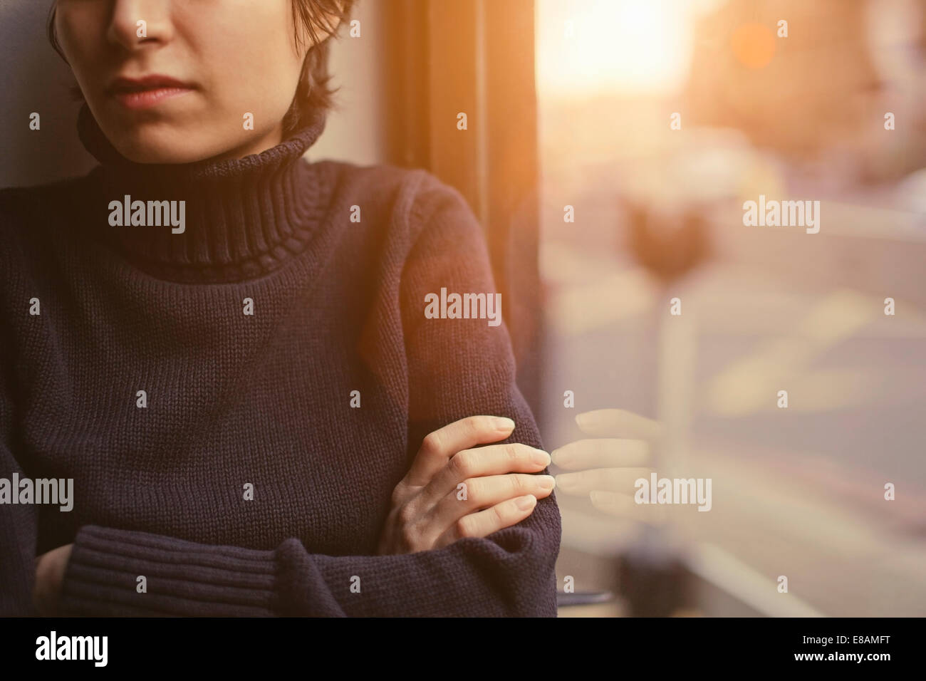 Ritagliato Ritratto di giovane donna con le braccia incrociate accanto alla finestra Foto Stock