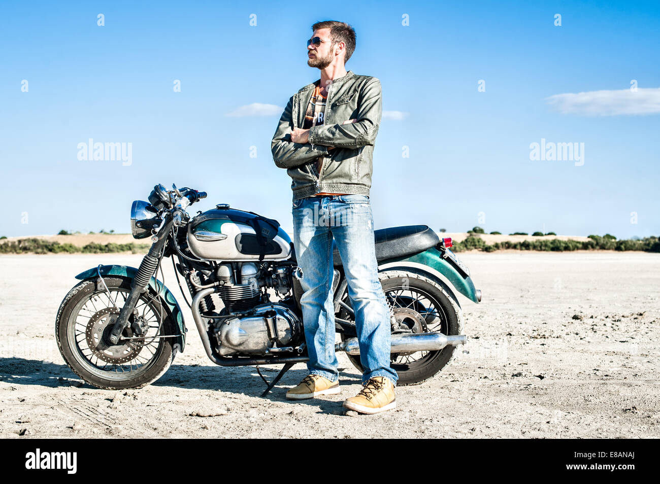 Ritratto di giovane maschio motociclista sulla pianura arida, Cagliari, Sardegna, Italia Foto Stock
