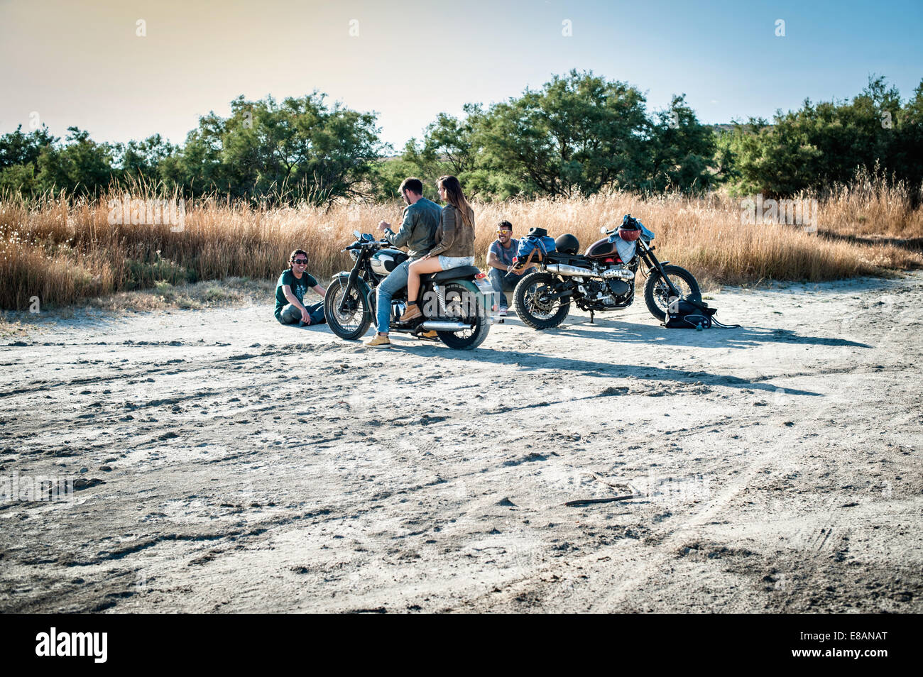 Quattro amici moto prendendo una pausa sulla pianura arida, Cagliari, Sardegna, Italia Foto Stock