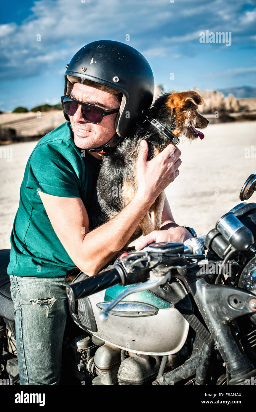 Metà uomo adulto e dog sitter su motociclo su arida pianura, Cagliari, Sardegna, Italia Foto Stock