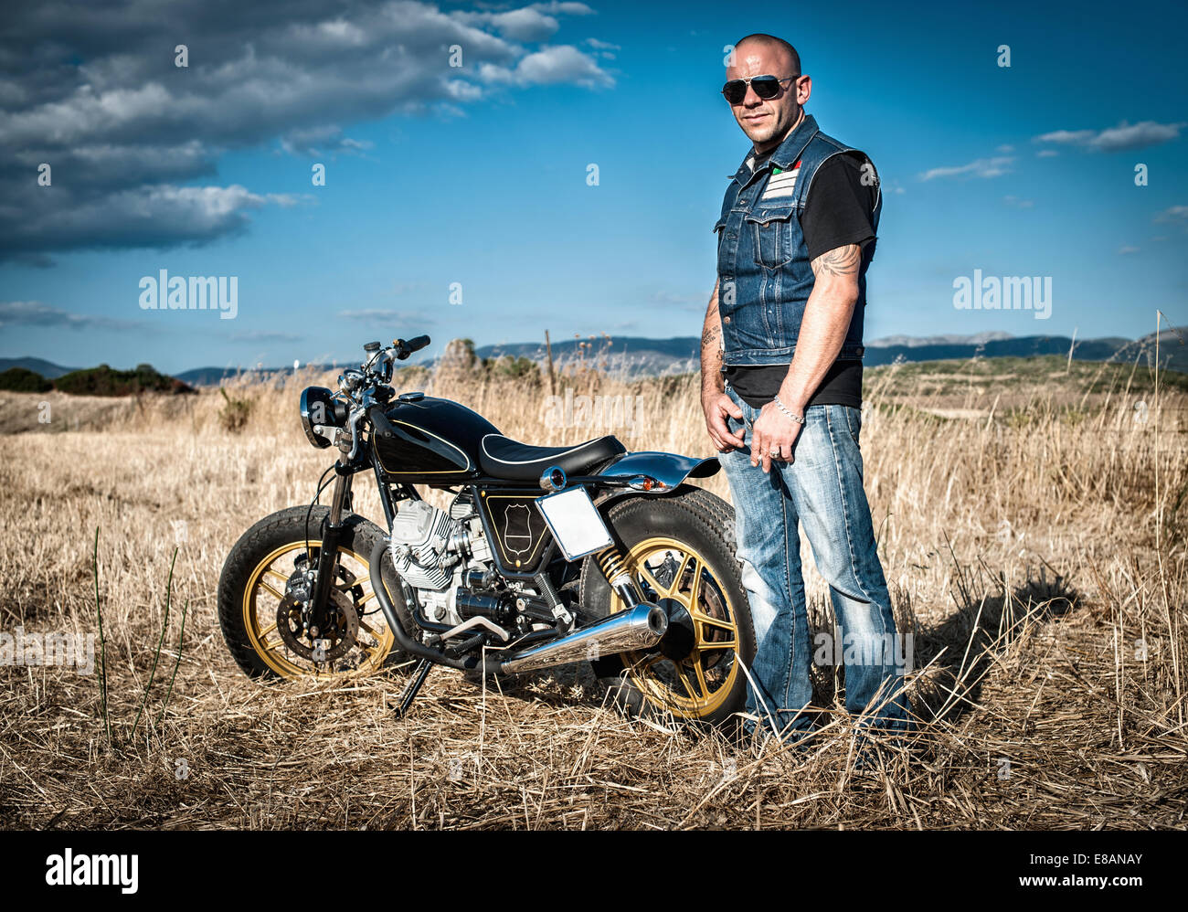 Ritratto del motociclista maschio nel paesaggio di pianura, Cagliari, Sardegna, Italia Foto Stock
