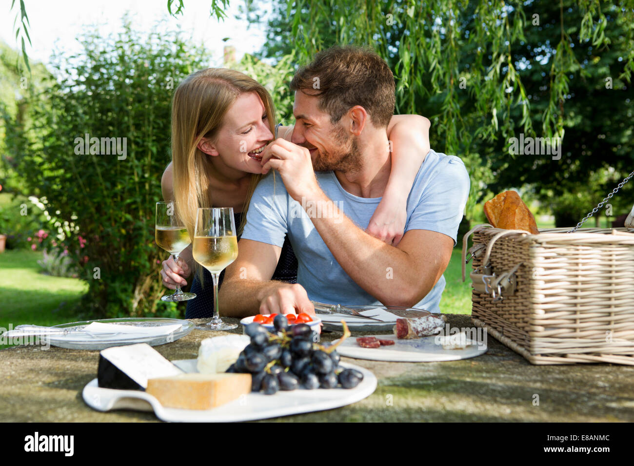 Metà uomo adulto alimentazione ragazza dal tavolo da picnic nel giardino Foto Stock