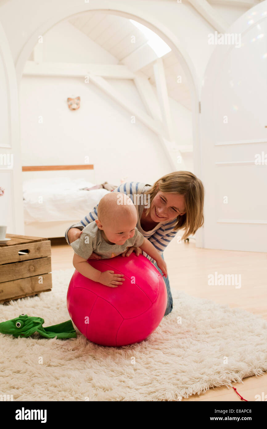 Coppia madre e figlia femmina sulla parte superiore della palla ginnica in salotto Foto Stock