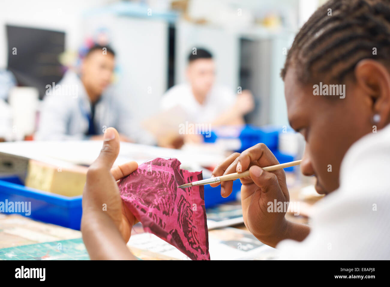 Studente maschio dipinto su swatch del tessuto in classe tessili Foto Stock
