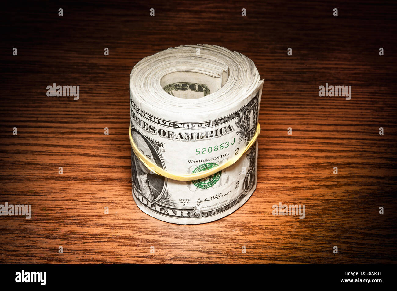 Rotolo di dollaro americano note avvolto in nastro elastico sulla scrivania in ufficio Foto Stock
