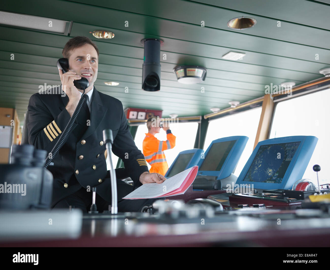 Capitano utilizzando il telefono sul ponte della nave Foto Stock