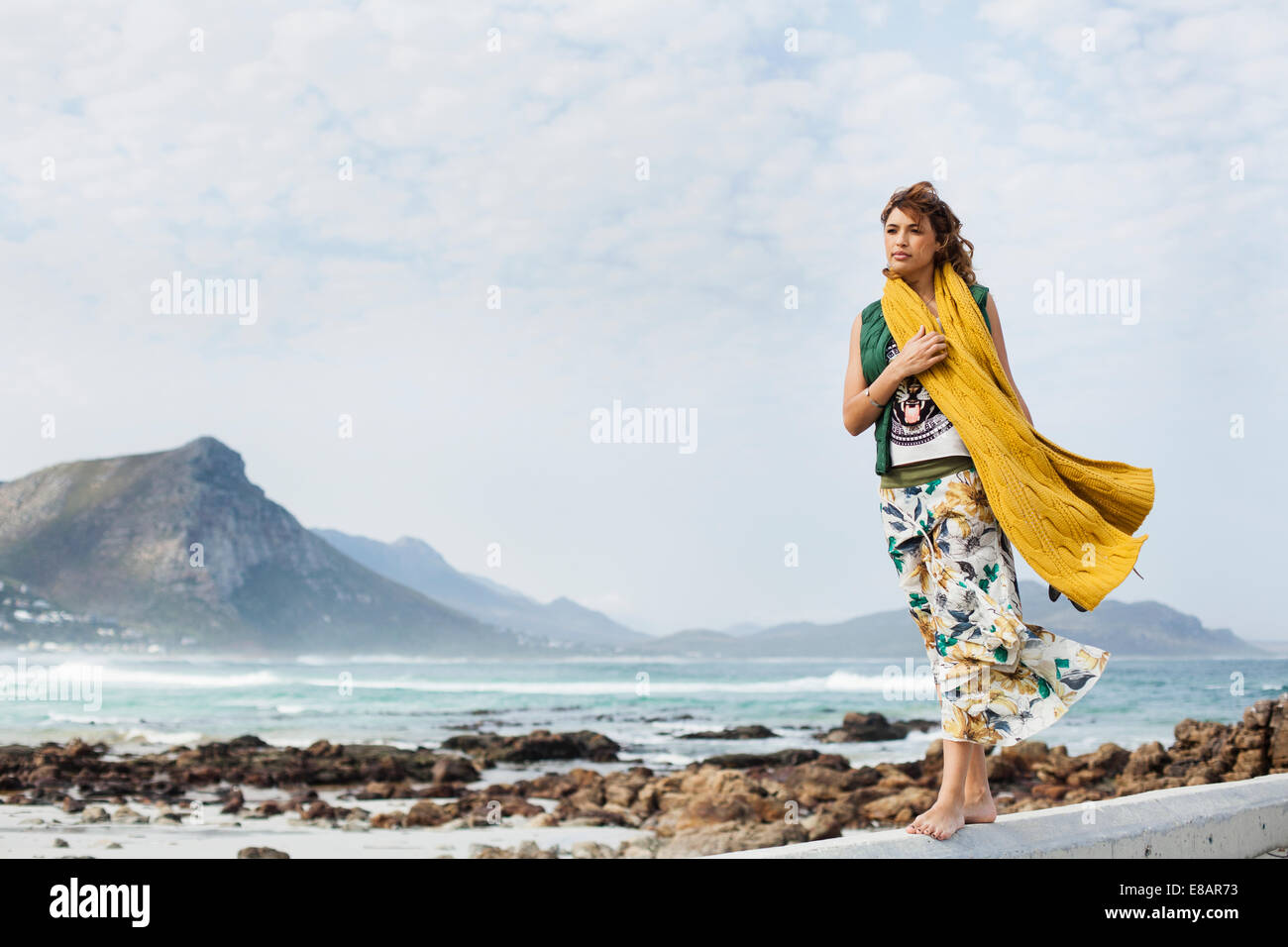 Giovane donna camminando lungo il blocco di cemento sulla spiaggia, Cape Town, Western Cape, Sud Africa Foto Stock