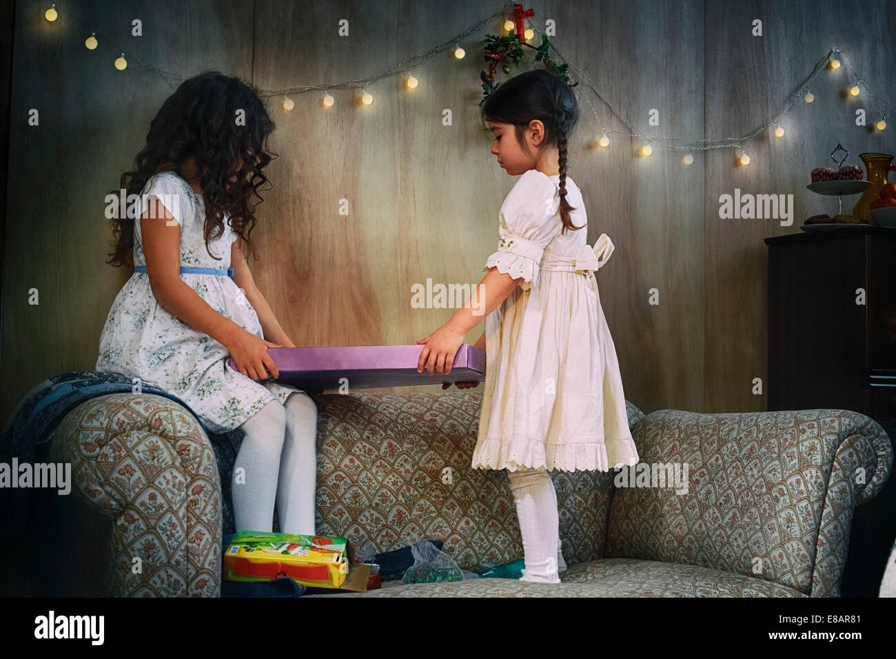 Sorelle in piedi sul salotto divano consegna regalo di natale Foto Stock