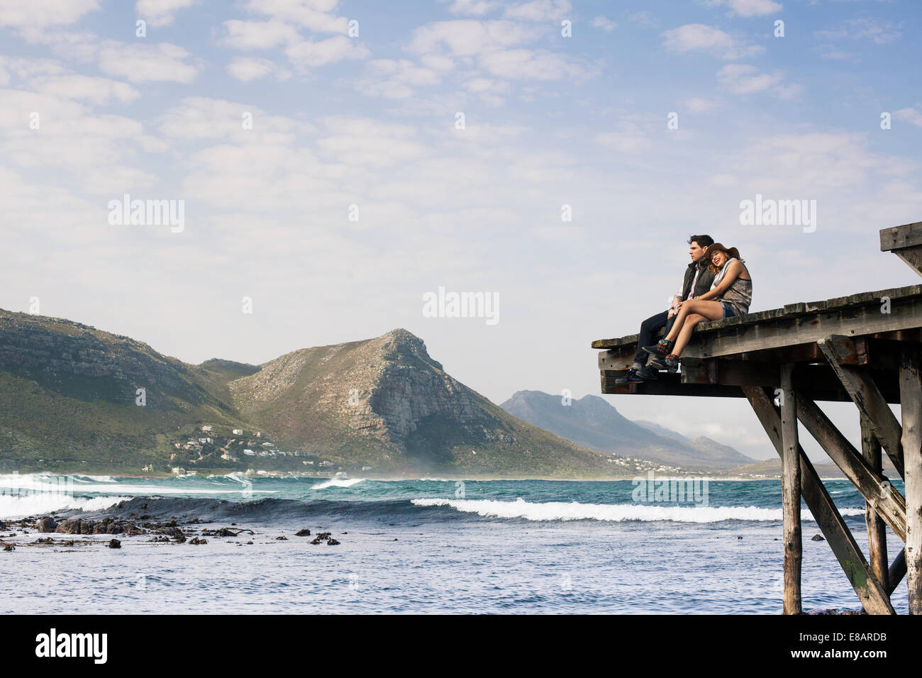 Coppia giovane seduto sul bordo del molo vecchio, Cape Town, Western Cape, Sud Africa Foto Stock