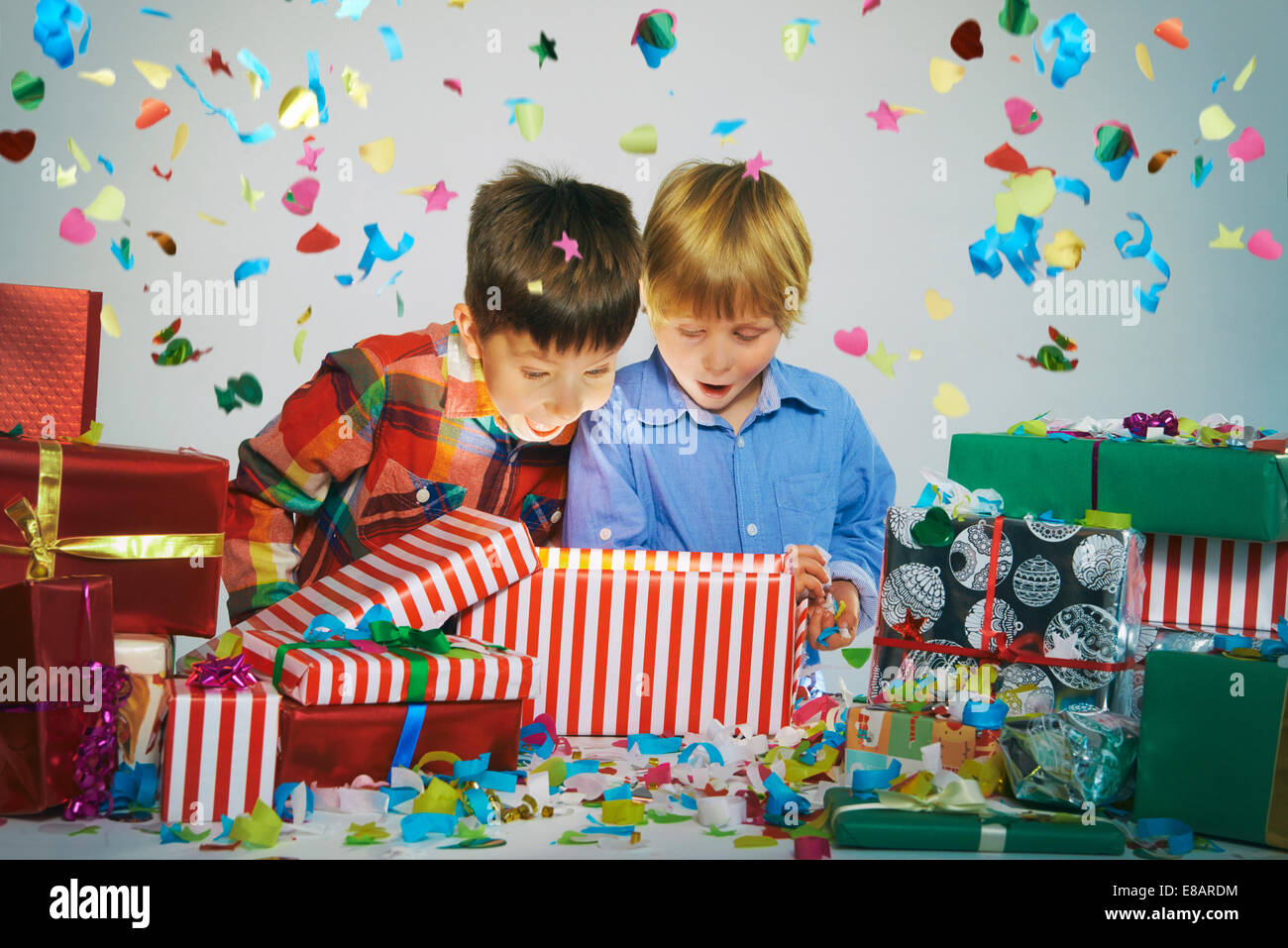 Due Fratelli con imboccatura aperta su disimballaggio incandescente regalo di Natale scatola con esplosione di coriandoli Foto Stock