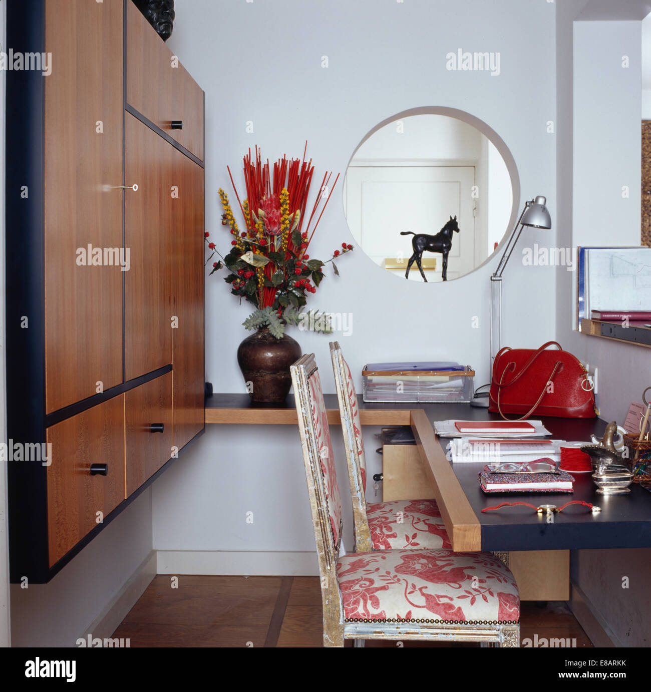 Piccola apertura circolare nella parete del piccolo moderno studio con montato ripostiglio imbottita e dipinti antichi sedie Foto Stock