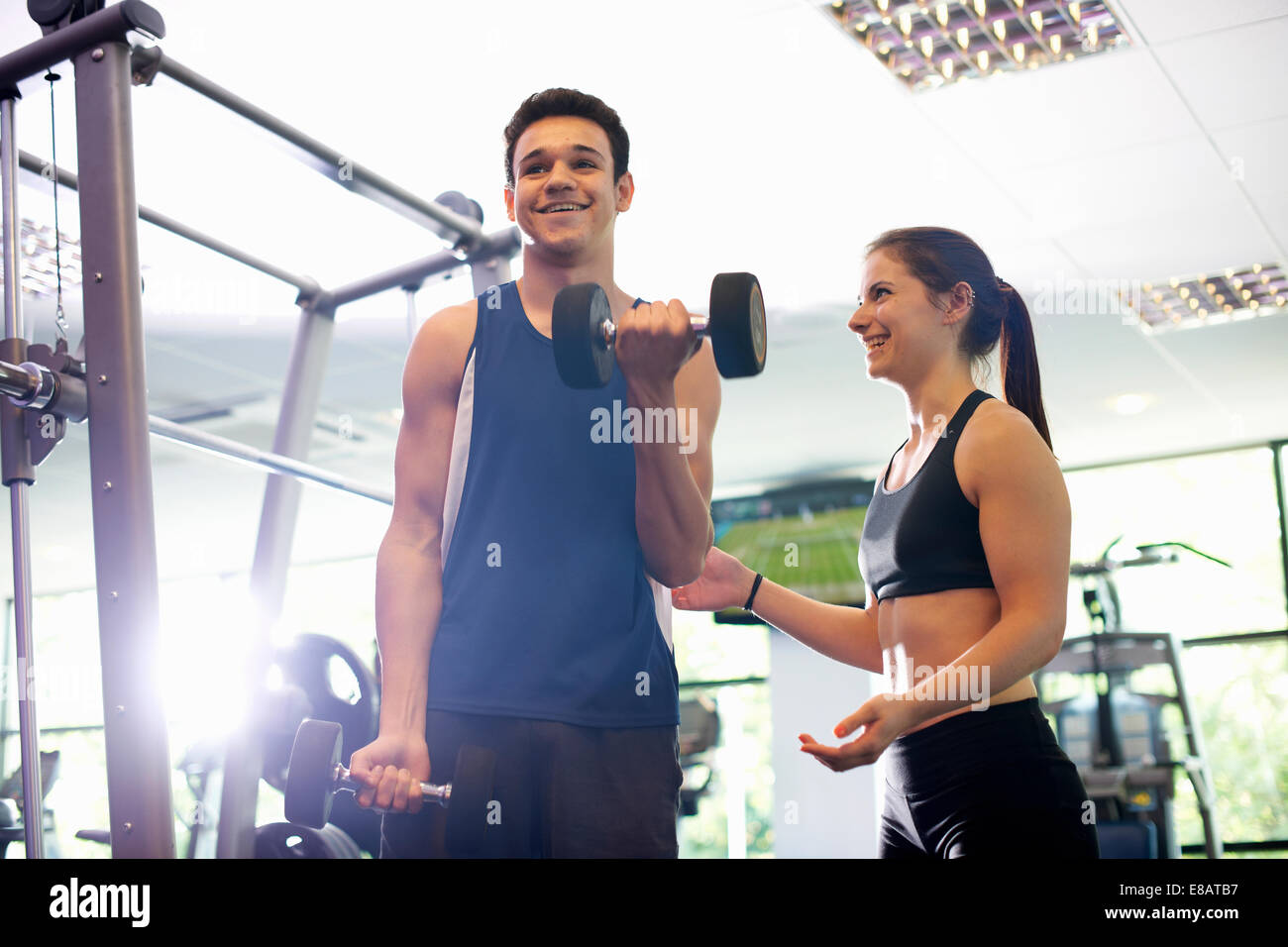 Personal trainer aiutando i giovani man mano di sollevamento pesi Foto Stock