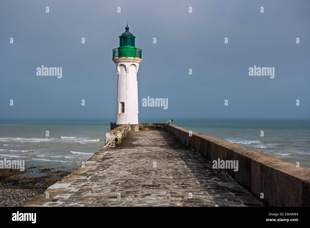 Faro e lonely man guardando il mare dal molo nel porto di Saint-Valery-en-Caux, Alta Normandia, Francia Foto Stock