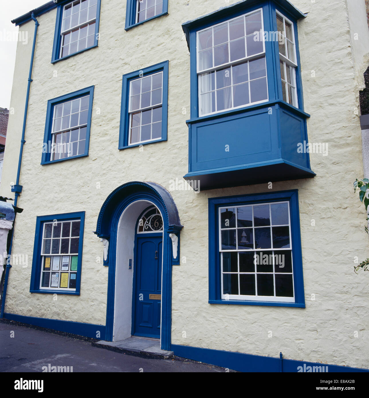 Crema tre piani di town-house con il blu dipinto di porte e finestre Foto Stock