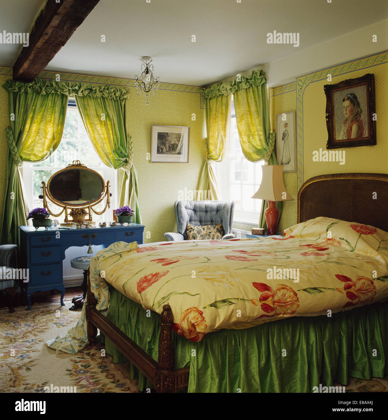 Verde pallido tende su finestra in giallo pallido camera da letto con motivi floreali e quilt valenza verde sul letto Foto Stock