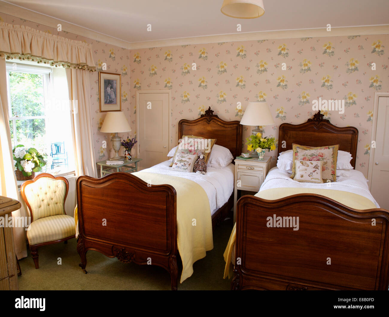 Arazzo cuscini e coperte di crema su letti antichi letti in mogano in paese camera da letto con rose carta da parati Foto Stock