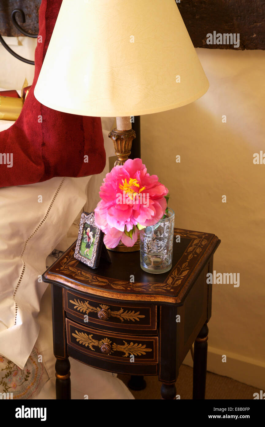 Close-up di crema e lampada singola paeony rosa su antiche intarsiato comodino Foto Stock