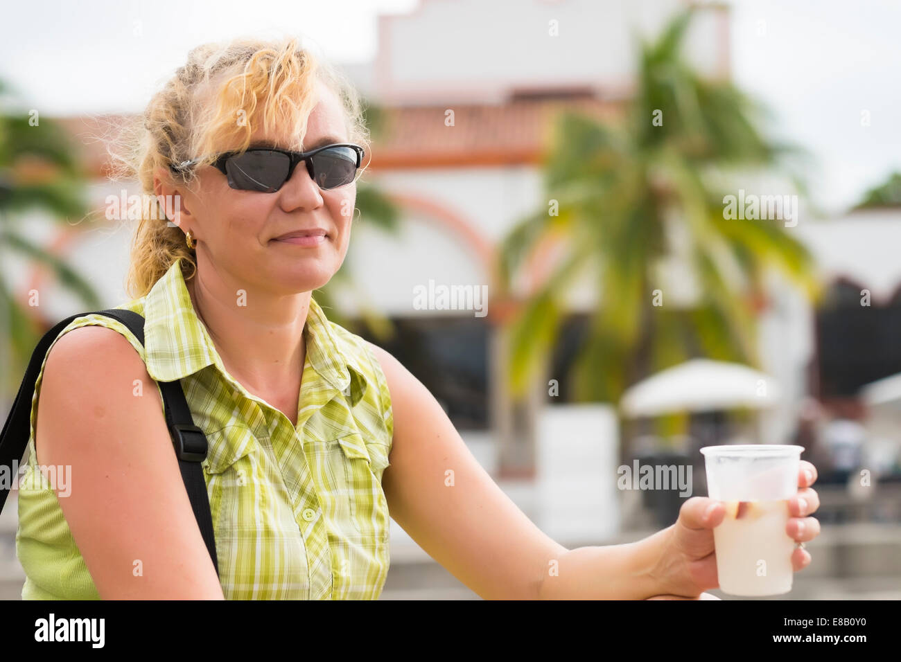 Turismo maturo donna avente un riposo e bere un drink rinfrescante in una tazza di plastica. Foto Stock