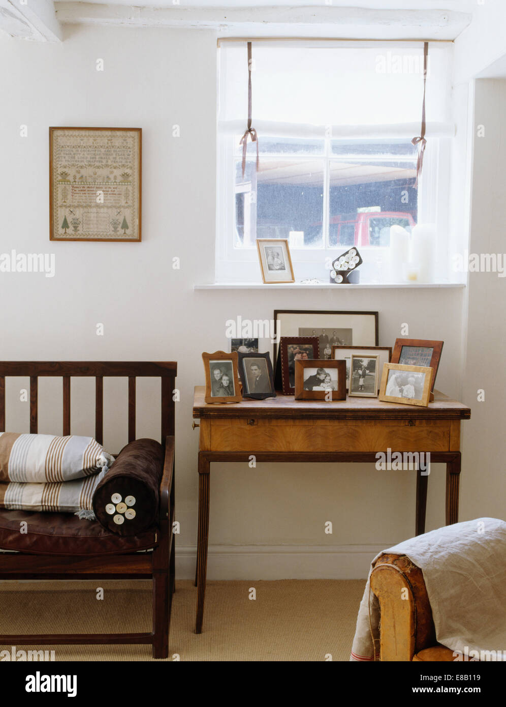Fotografie sul piccolo tavolo antico sotto la finestra con tenda bianca in bianco cottage soggiorno Foto Stock