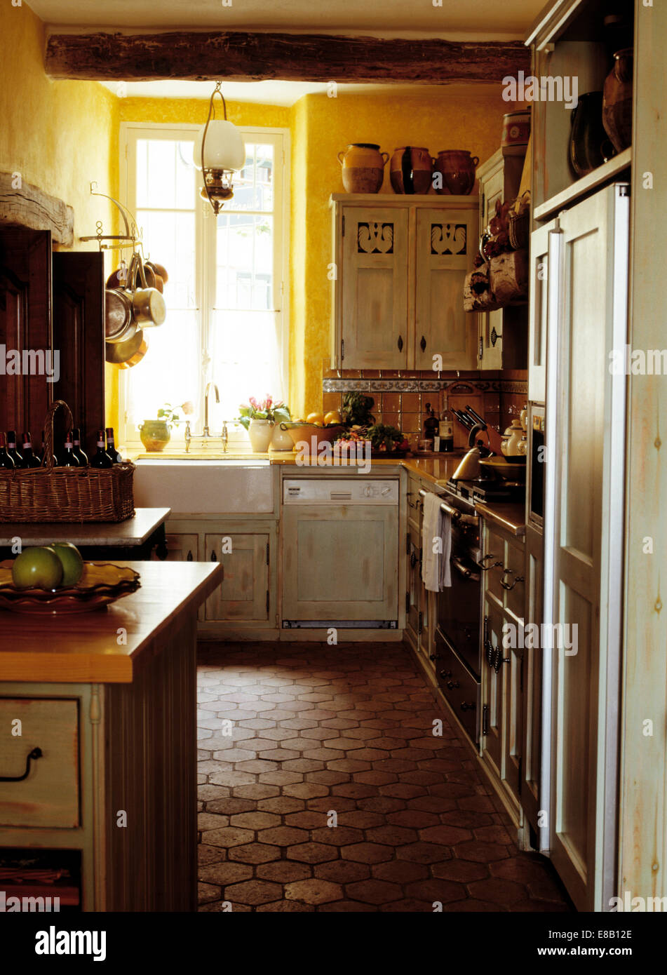 Esagonale a pavimento in piastrelle di terracotta in giallo cottage  francese cucina con lavastoviglie montato accanto a scatola montata con  lavandino in porcellana Foto stock - Alamy