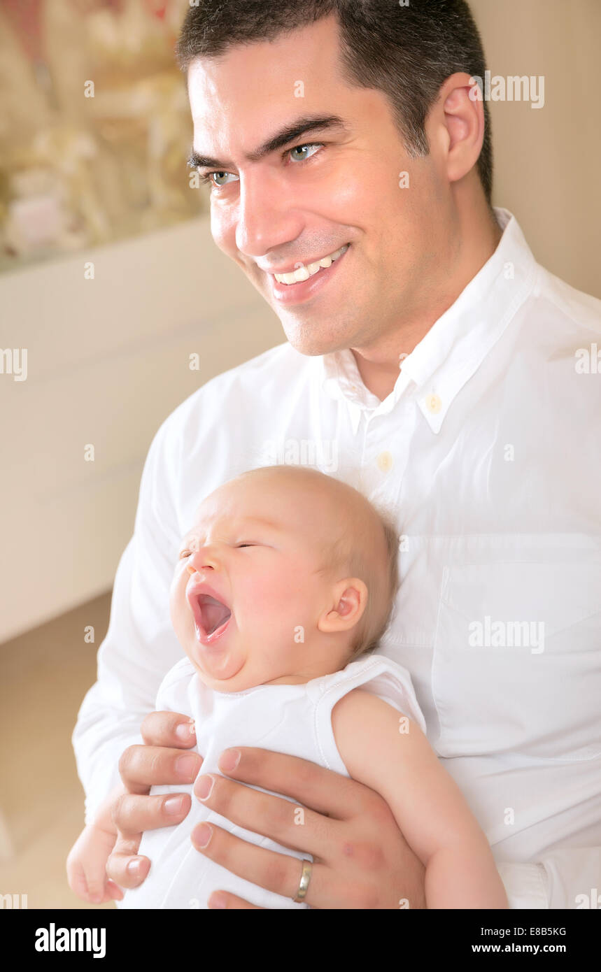 Padre Felice con sbadigli figlia sulle mani della casa, godendo di coricarsi, allegro la paternità, di amore e di felicità concept Foto Stock