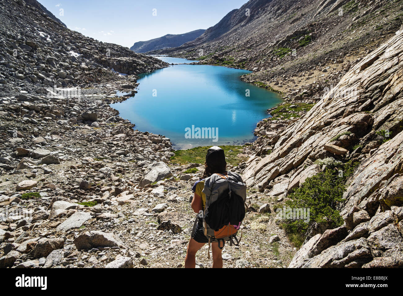 Vista posteriore di una donna backpacker guardando verso il basso in corrispondenza di laghi glaciali in Darwin Canyon di Kings Canyon National Park Foto Stock