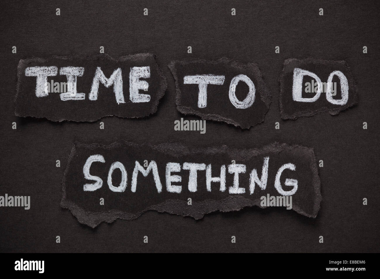 Frammenti di carta nera e le parole " Tempo di fare qualcosa". Close-up. Foto Stock