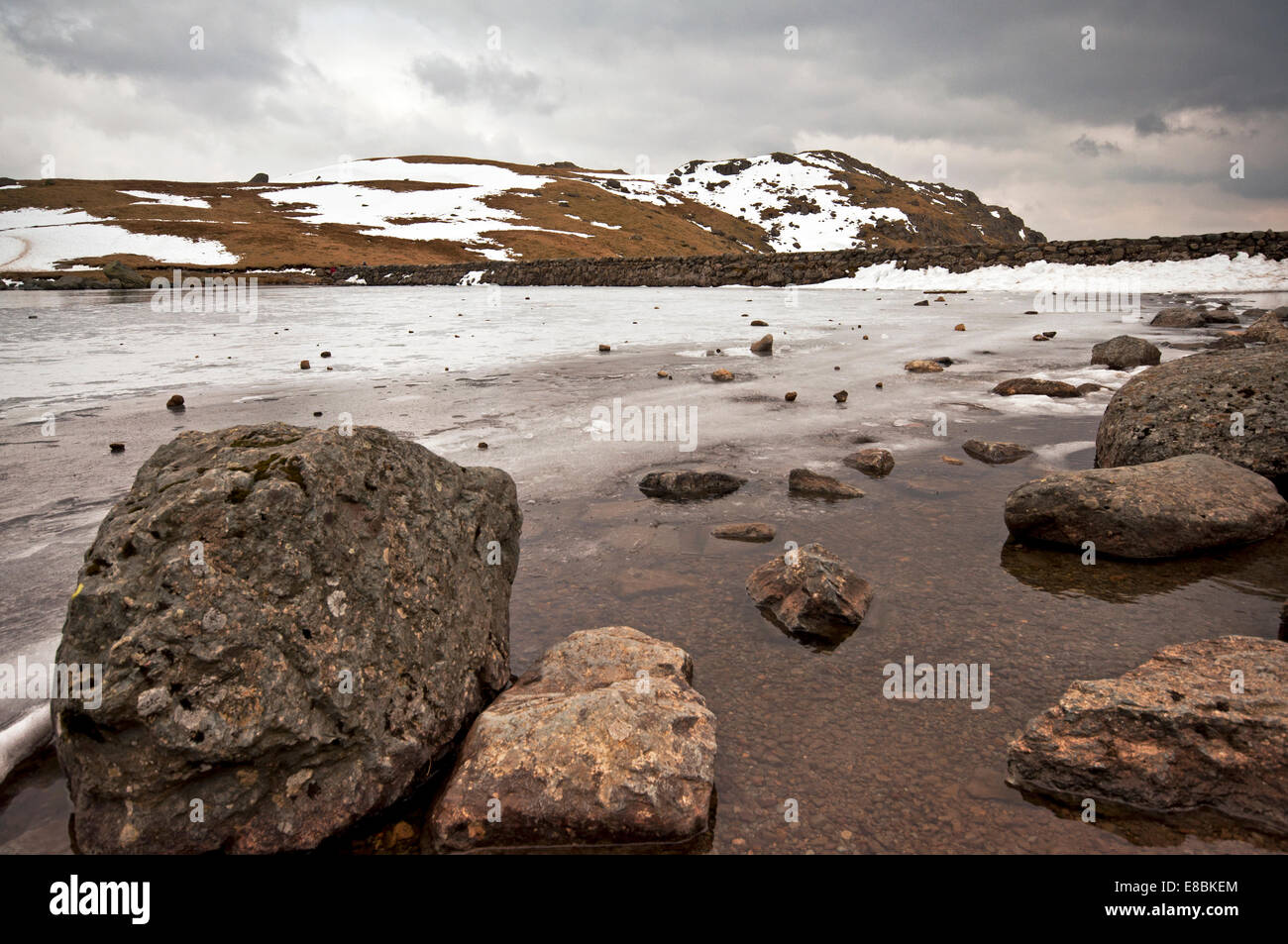 Un congelati Stickle Tarn nel Parco Nazionale del Distretto dei Laghi. La diga di parete può essere visto con derive di neve nella parte anteriore di essa. Foto Stock