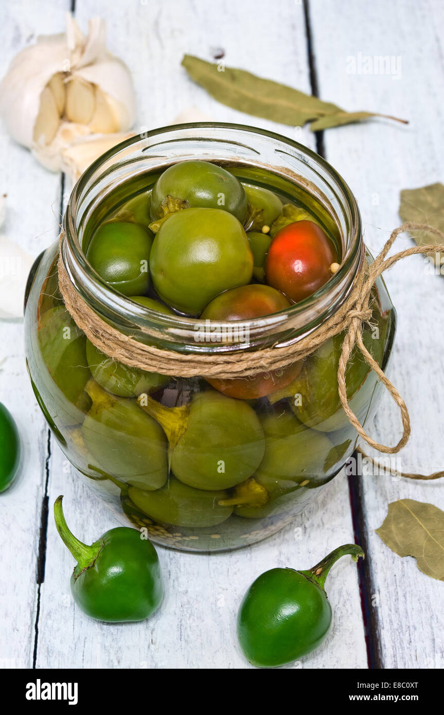 Un vaso con appena raccolto peperoncini rossi conservati in aceto, su una tavola in legno rustico Foto Stock