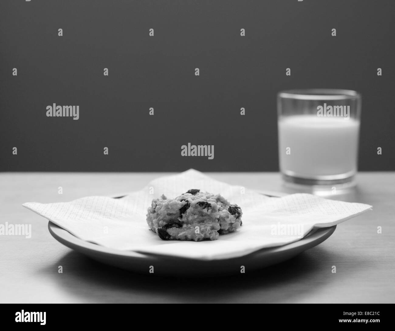 Farina di avena raisin cookie su una piastra con un bicchiere di latte in background - elaborazione monocromatica Foto Stock