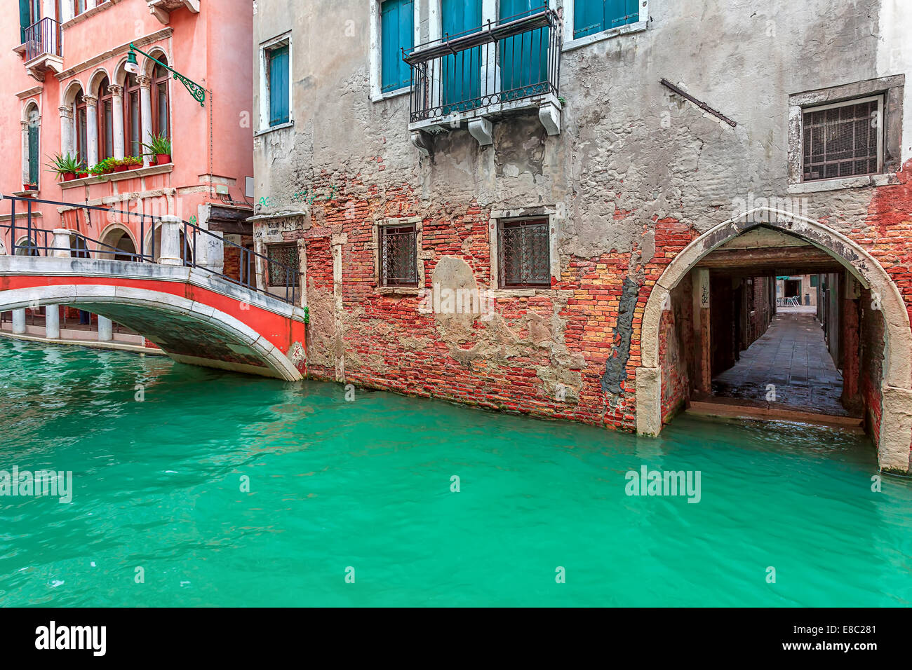 Stretto canale lungo la vecchia casa di mattoni e piccolo ponte a Venezia, Italia. Foto Stock