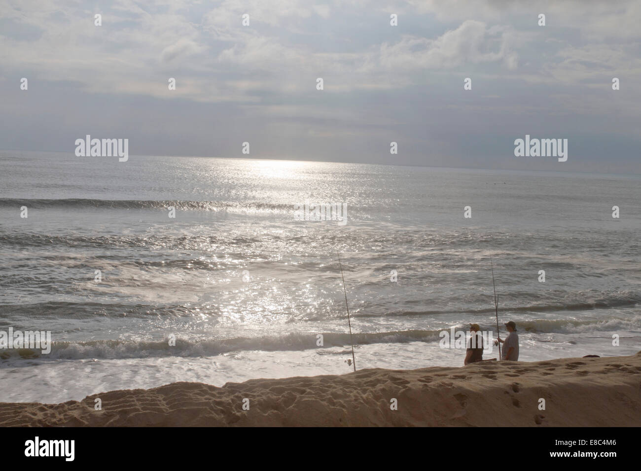 Due pescatori di pesce companionable insieme nell'oceano su una spiaggia di Cape Hatteras, NC vicino al tramonto Foto Stock