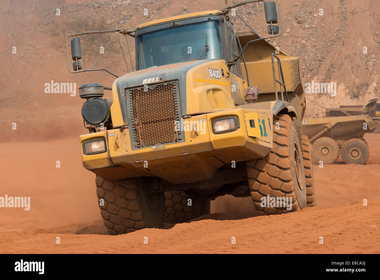 Un piccolo carrello minerario porta ferro ricco suolo laterite lontano da un laghetto di acqua sito in costruzione in corrispondenza di una fossa aperta miniera di rame. Foto Stock