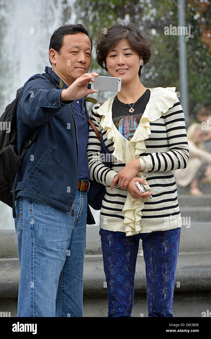 Un asiatico giovane prendendo un selfie vicino alla fontana di Washington Square Park nel Greenwich Village di New York City Foto Stock