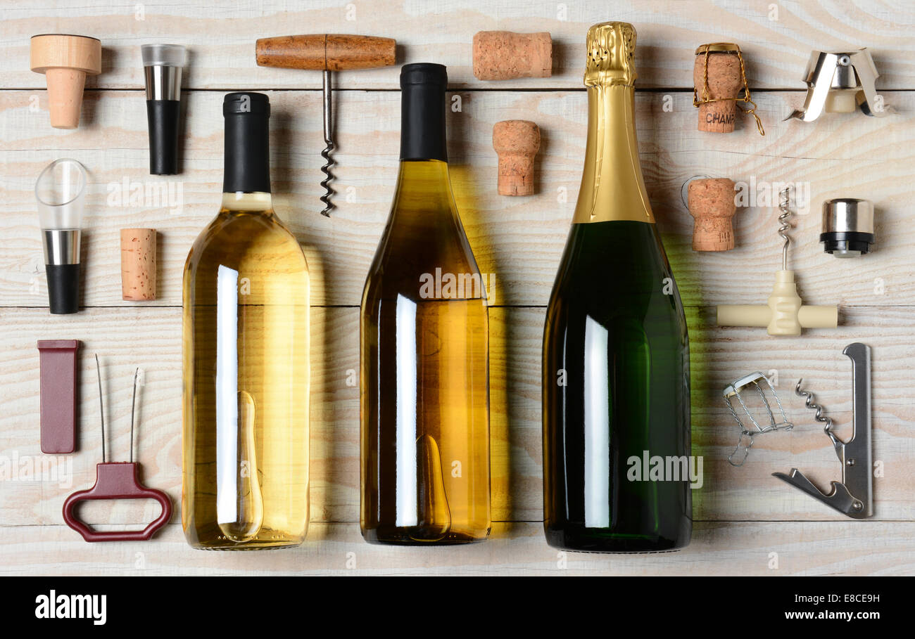Alta angolazione del vino e bottiglie di Champagne circondato da accessori come cavatappi, tappi, versatore e tappi in sughero. Orizzonte Foto Stock