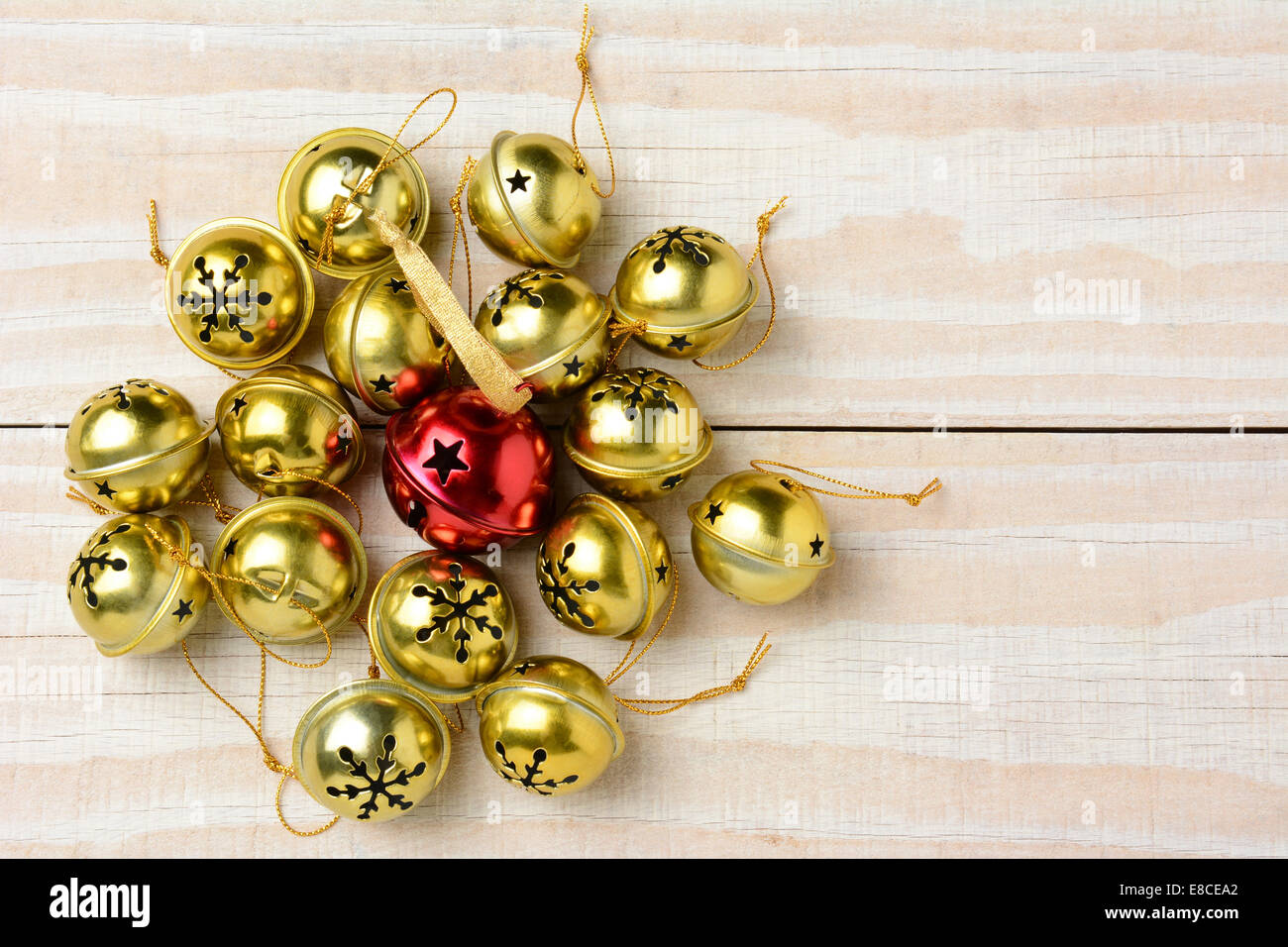 Alta angolazione di un gruppo di Natale Jingle Bells su un bianco tavola di legno. Formato orizzontale con una campana rossa circondata da un Foto Stock