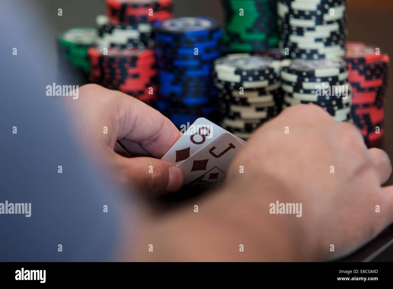 Parted carta in mano, J8, e una partita di poker chips Foto Stock