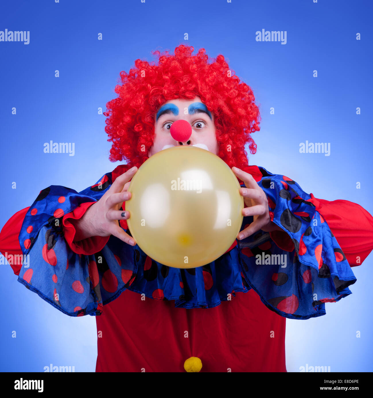 Clown in costume rosso con palloncino in mani su sfondo blu Foto Stock