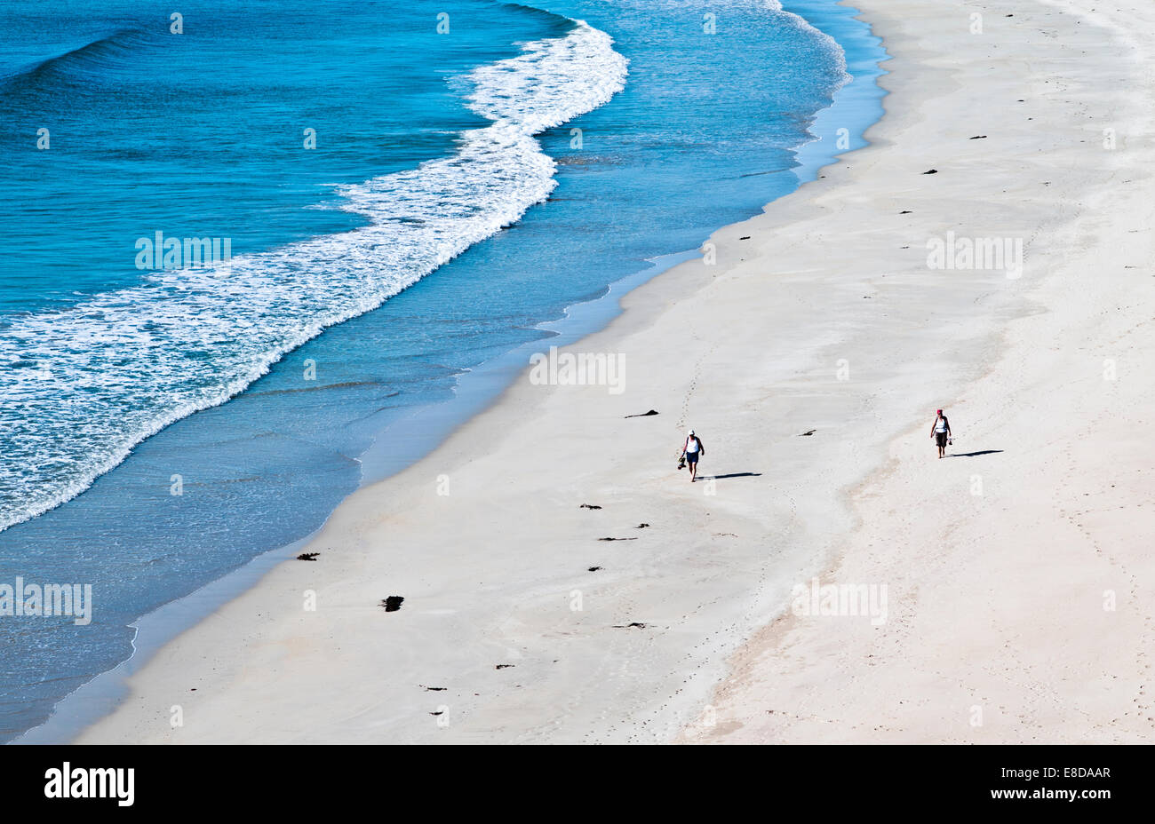 Giovane camminare a piedi scalzi lungo una bellissima spiaggia di sabbia sul bordo dell'acqua, caldo sole estivo, Balnakeil Bay Sutherland Scozia Scotland Foto Stock