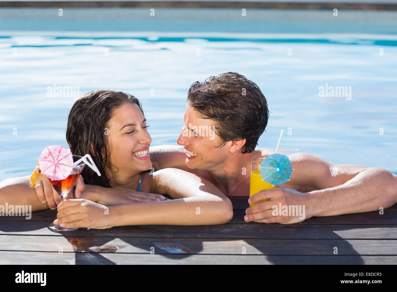 Allegro giovane con bevande in piscina Foto Stock