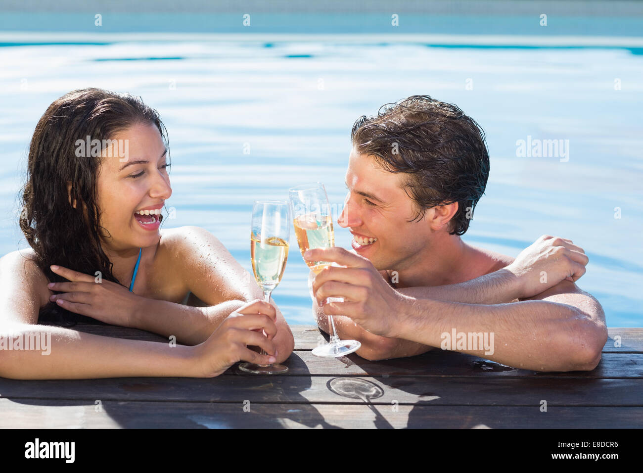 Allegro giovane tostare champagne in piscina Foto Stock