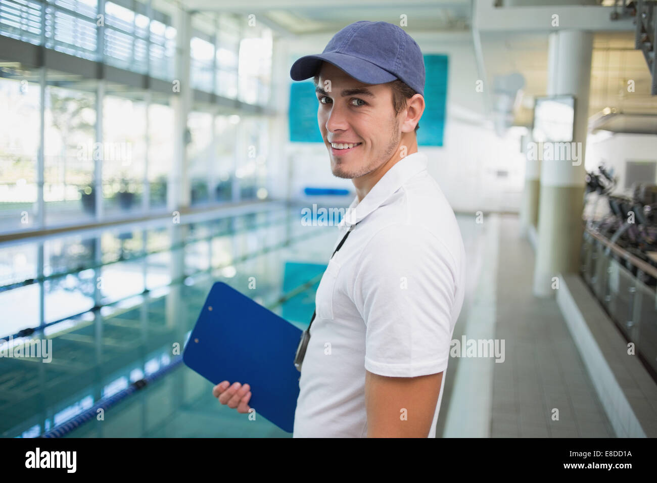 Istruttore di nuoto di sorridere alla telecamera tramite la piscina Foto Stock