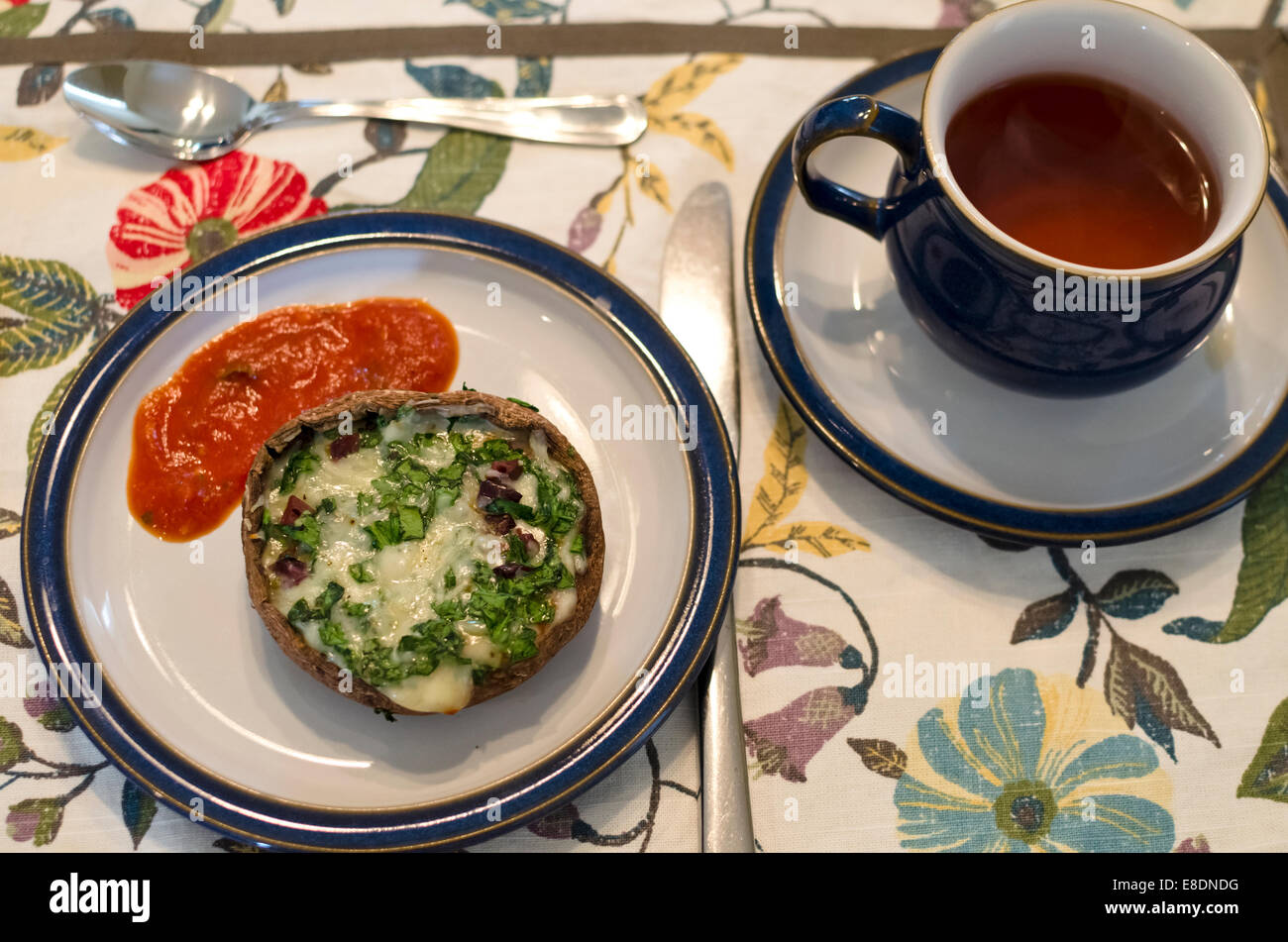 Portabello Funghi ripieni di formaggio fuso e erbe aromatiche fresche, servita con una salsa di pomodoro. Come antipasto per il tè del pomeriggio. Foto Stock