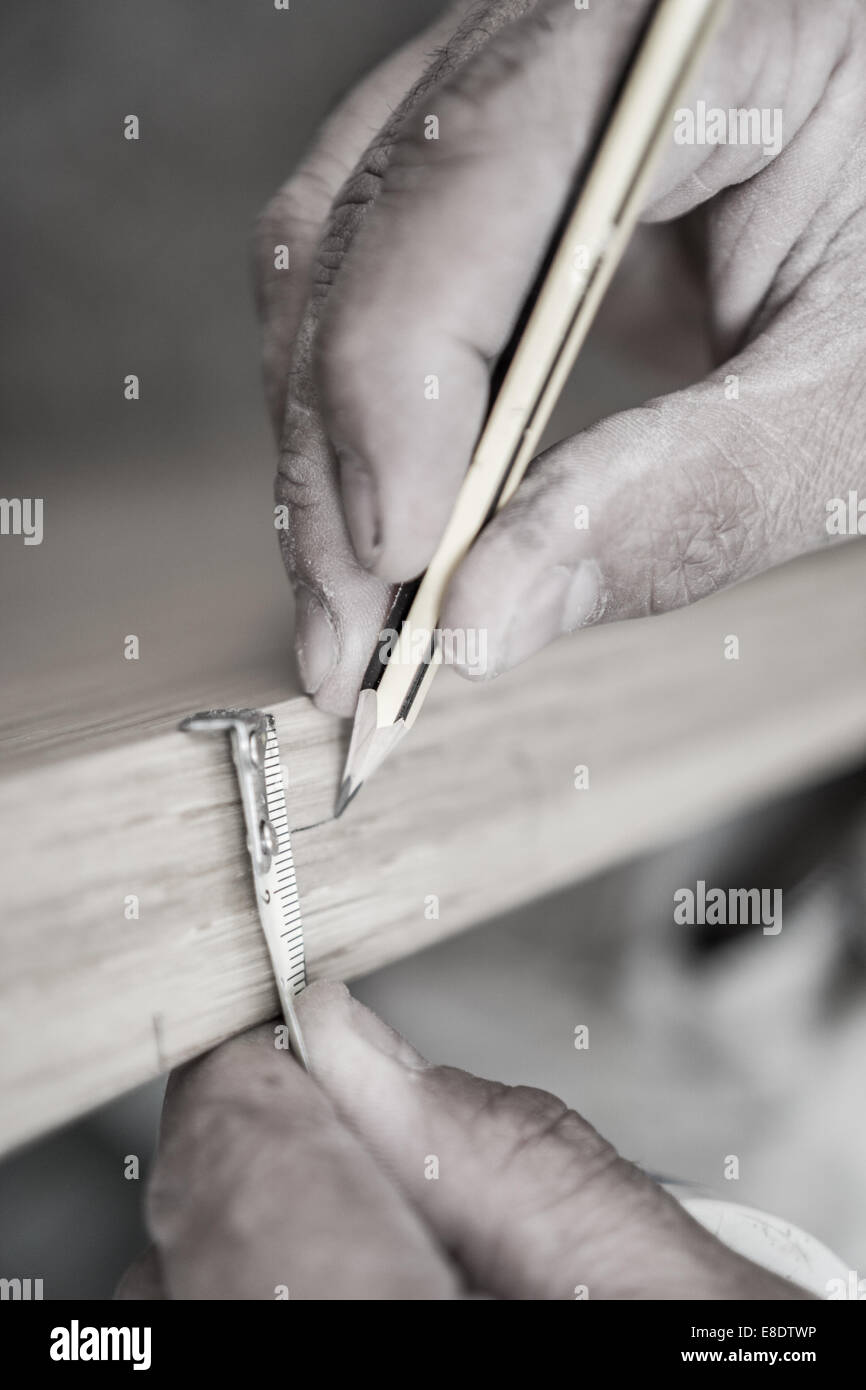 Tonalità seppia closeup di carpenter con matita lavorando sullo sportello Foto Stock