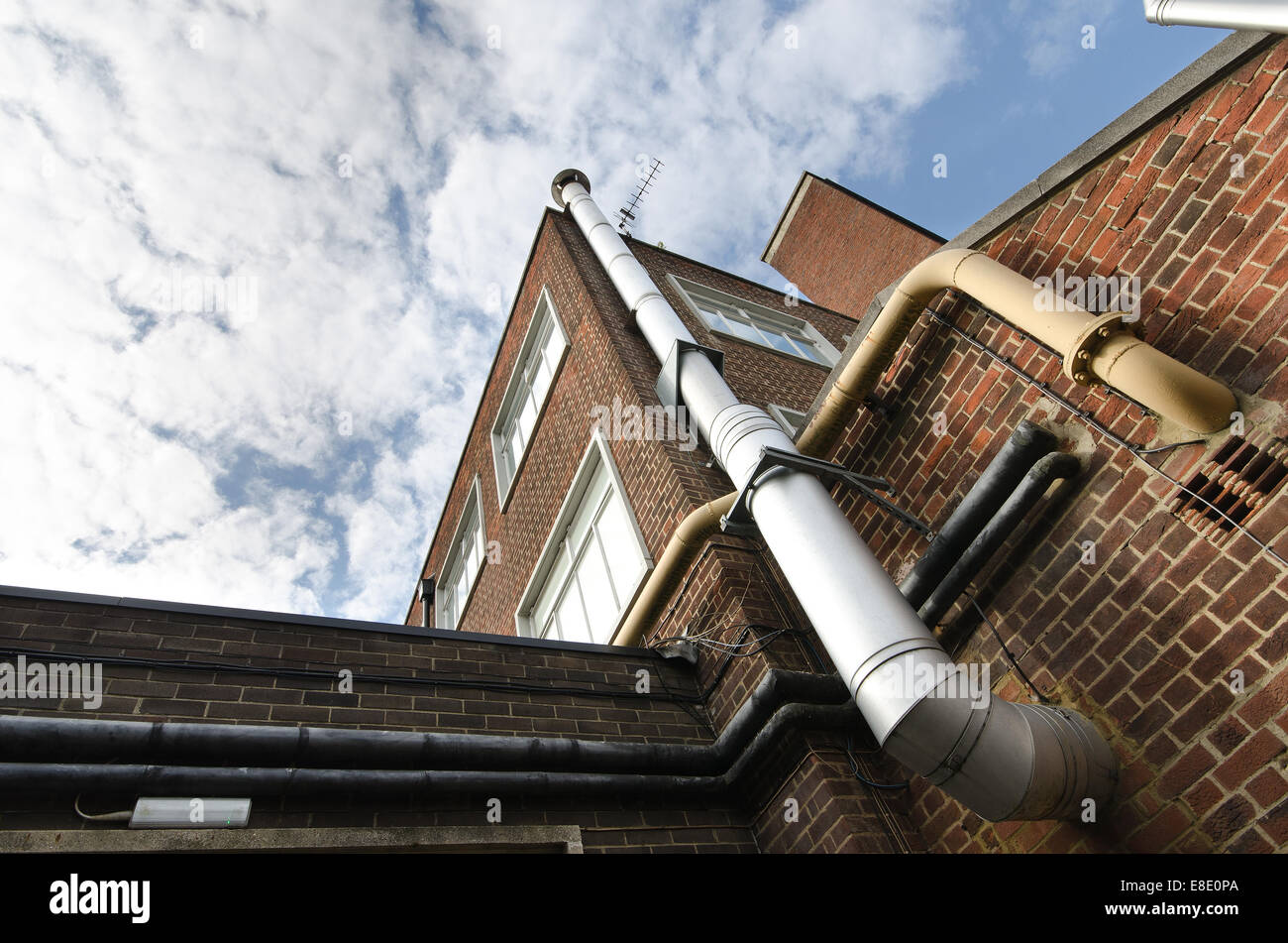 Canna fumaria metallica e il camino in acciaio con tubi di riscaldamento al di fuori di un edificio di mattoni non torre una energia efficiente sistema Foto Stock