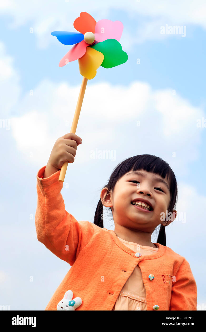 Carino bambina su erba nel giorno di estate detiene il mulino a vento per adv o altri usi Foto Stock