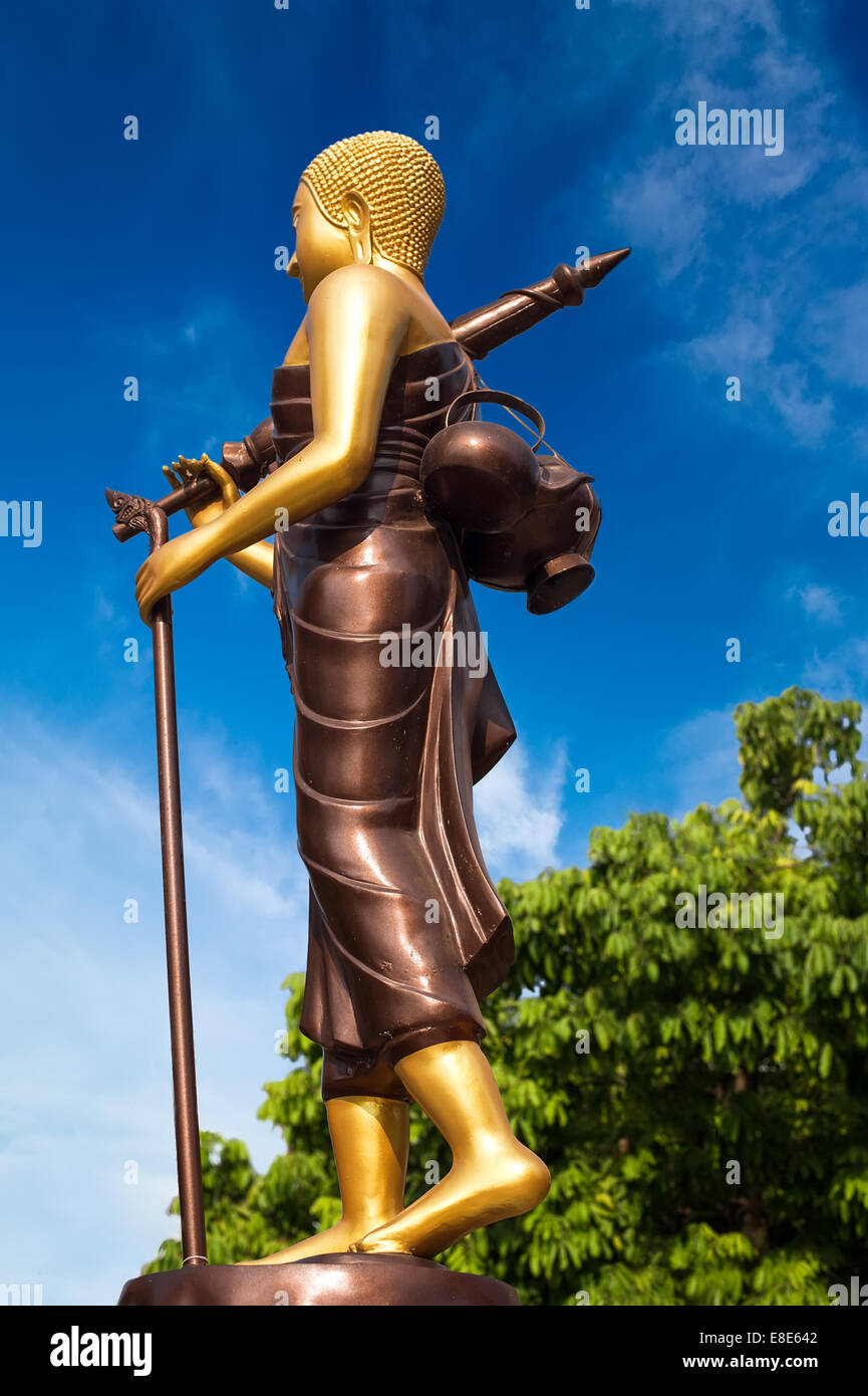 Statua di Buddha a piedi in tradizionale stile theravada con ombrellone e ciotola. Città asiatiche architettura religiosa a livello pubblico plac Foto Stock