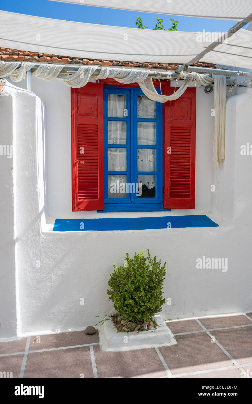 Finestra blu con persiane rosse sul muro bianco Grecia KOS Foto Stock