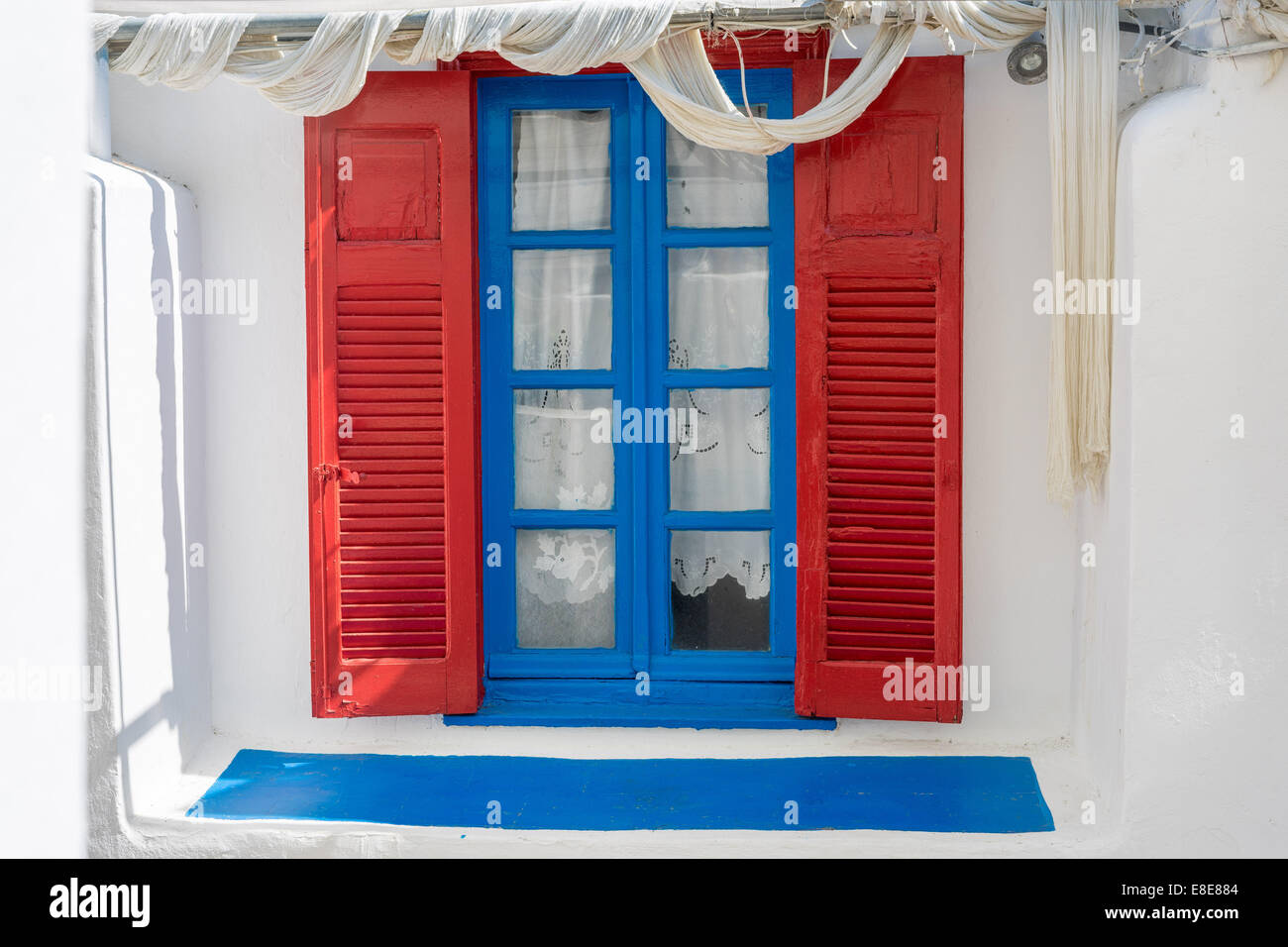 Finestra blu con persiane rosse sul muro bianco Grecia KOS Foto Stock